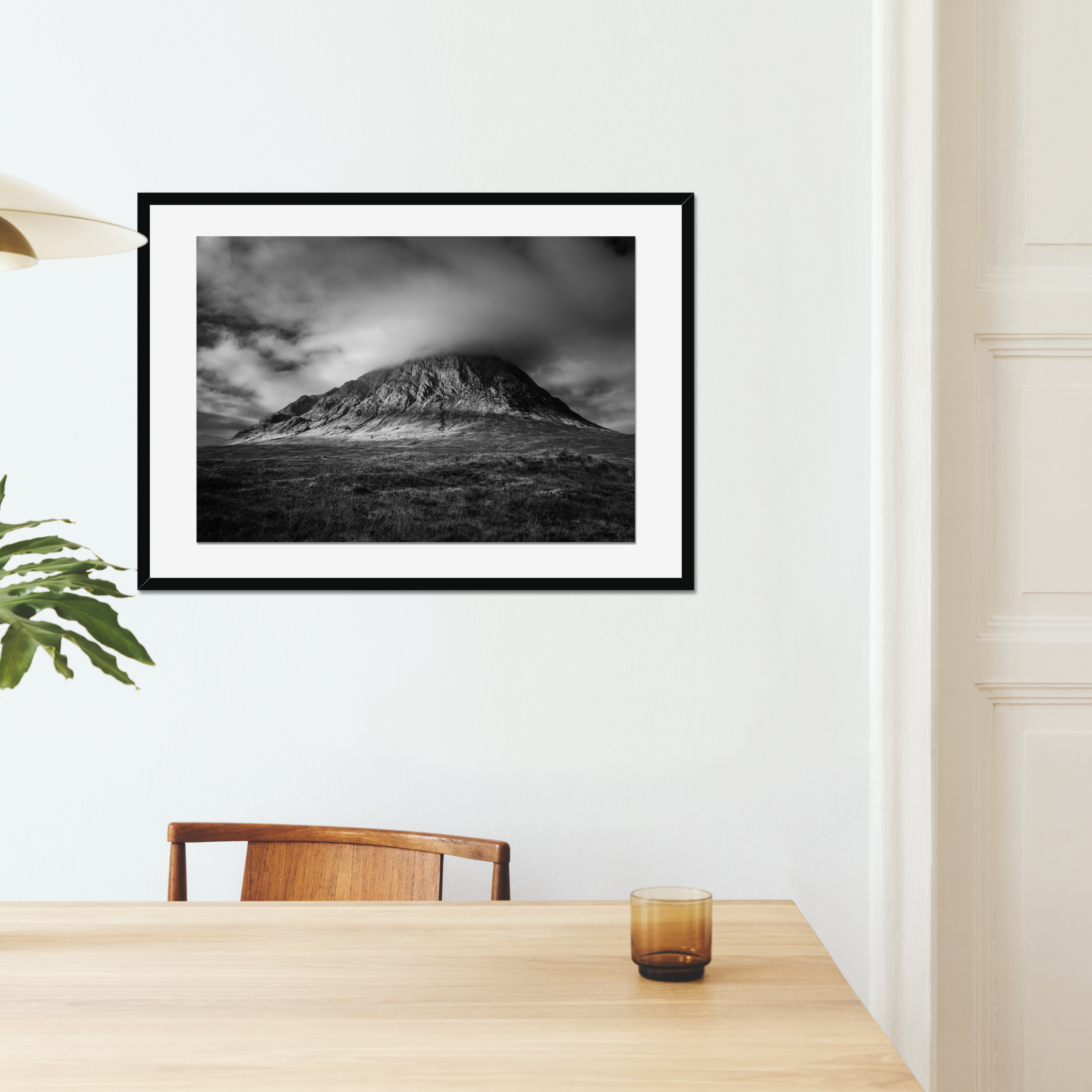 Black and white photograph of Buachaille Etive Mòr in Glencoe, with dramatic storm clouds gathering over the mountain and light breaking across its slopes.