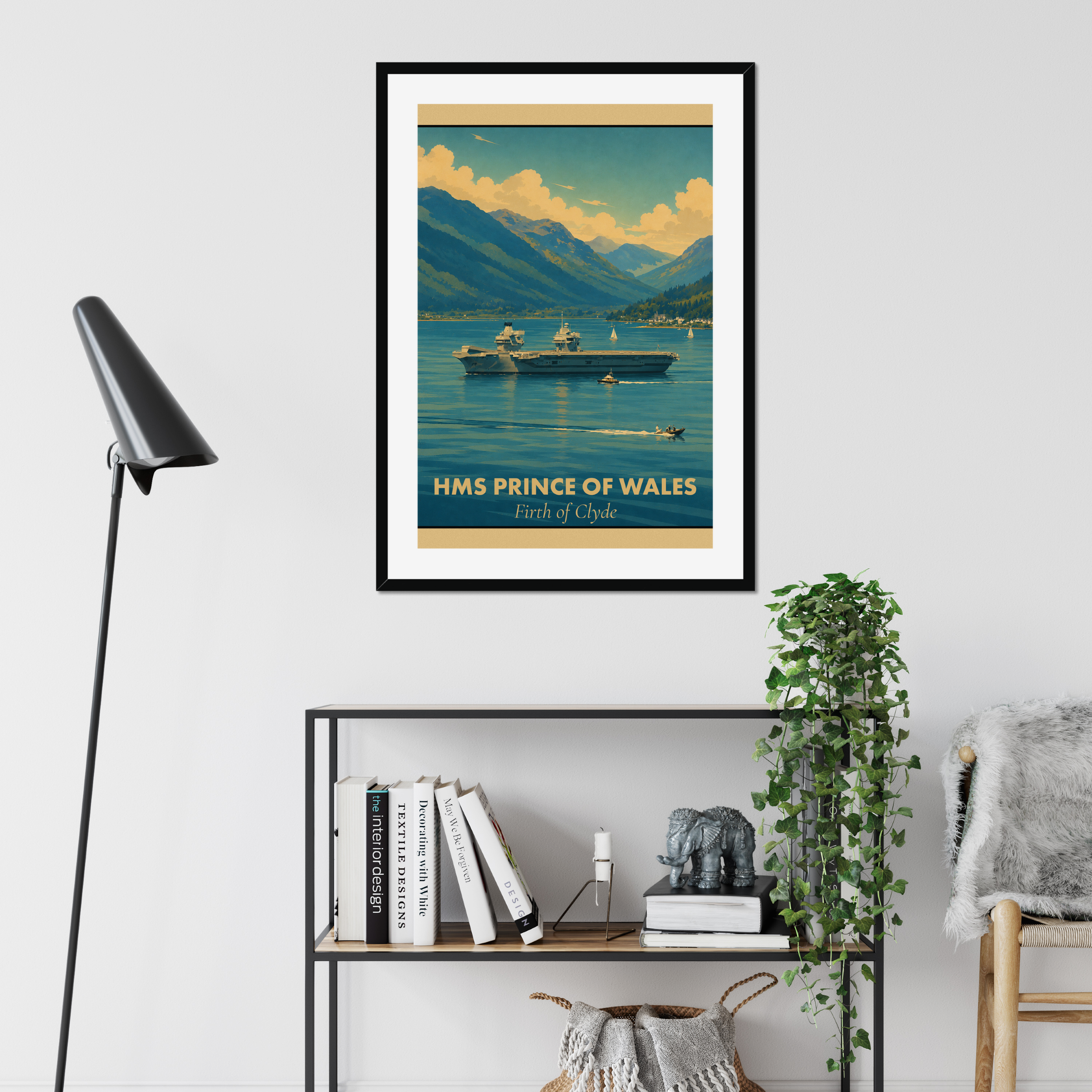 Framed poster of HMS Prince of Wales on a wall above a shelf with books and decor.