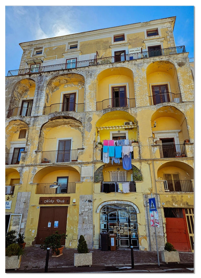 Panni al Sole fine art photograph of a weathered yellow Italian building with balconies and colourful washing in the sunshine