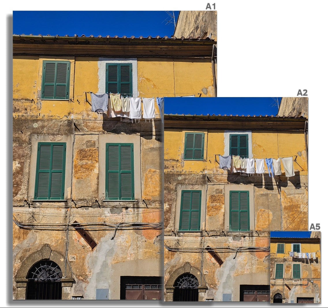 Panni al Vento fine art photograph of washing hanging outside a weathered Italian building with green shutters